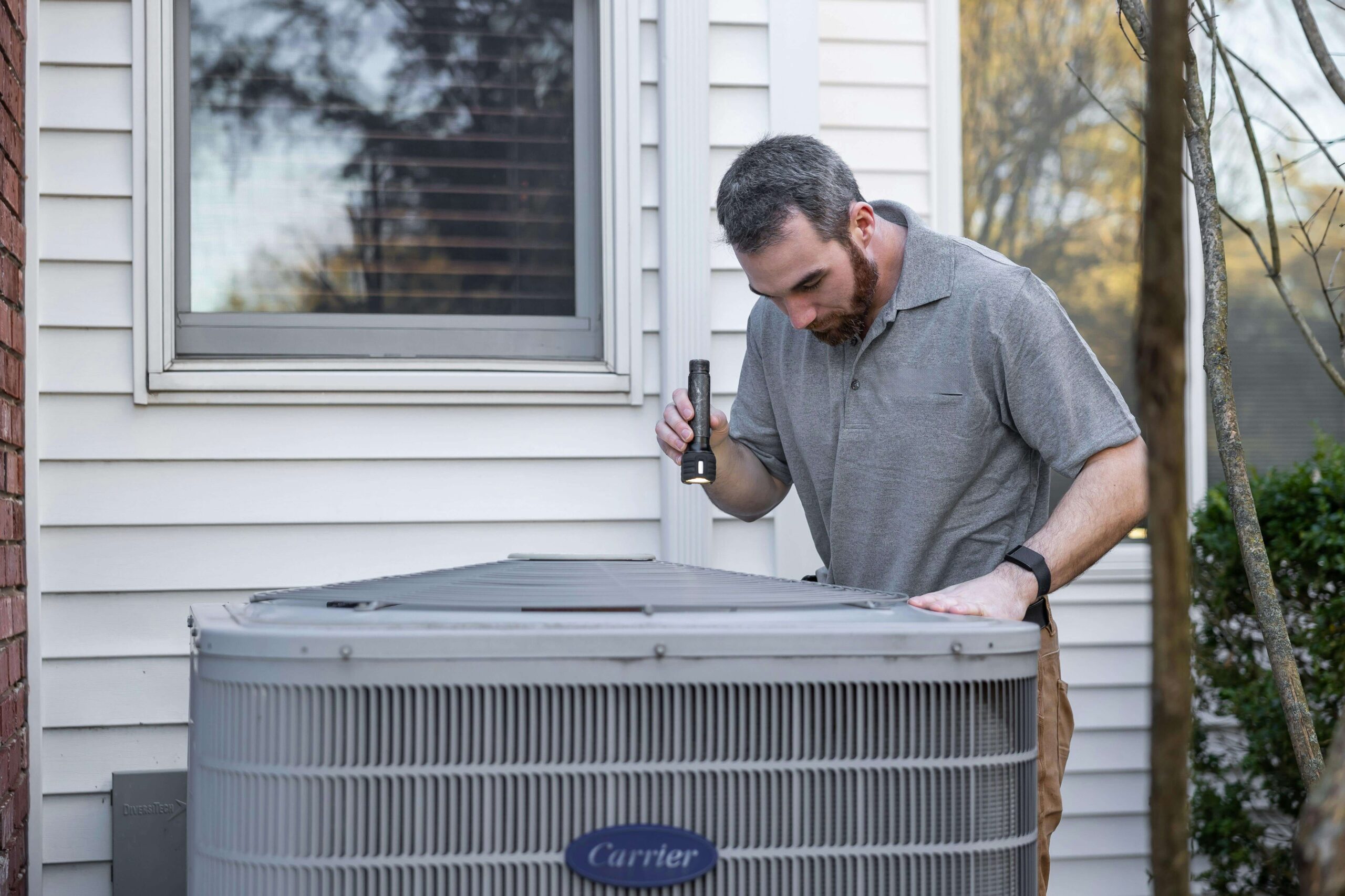 HVAC technician inspecting an outdoor HVAC unit.