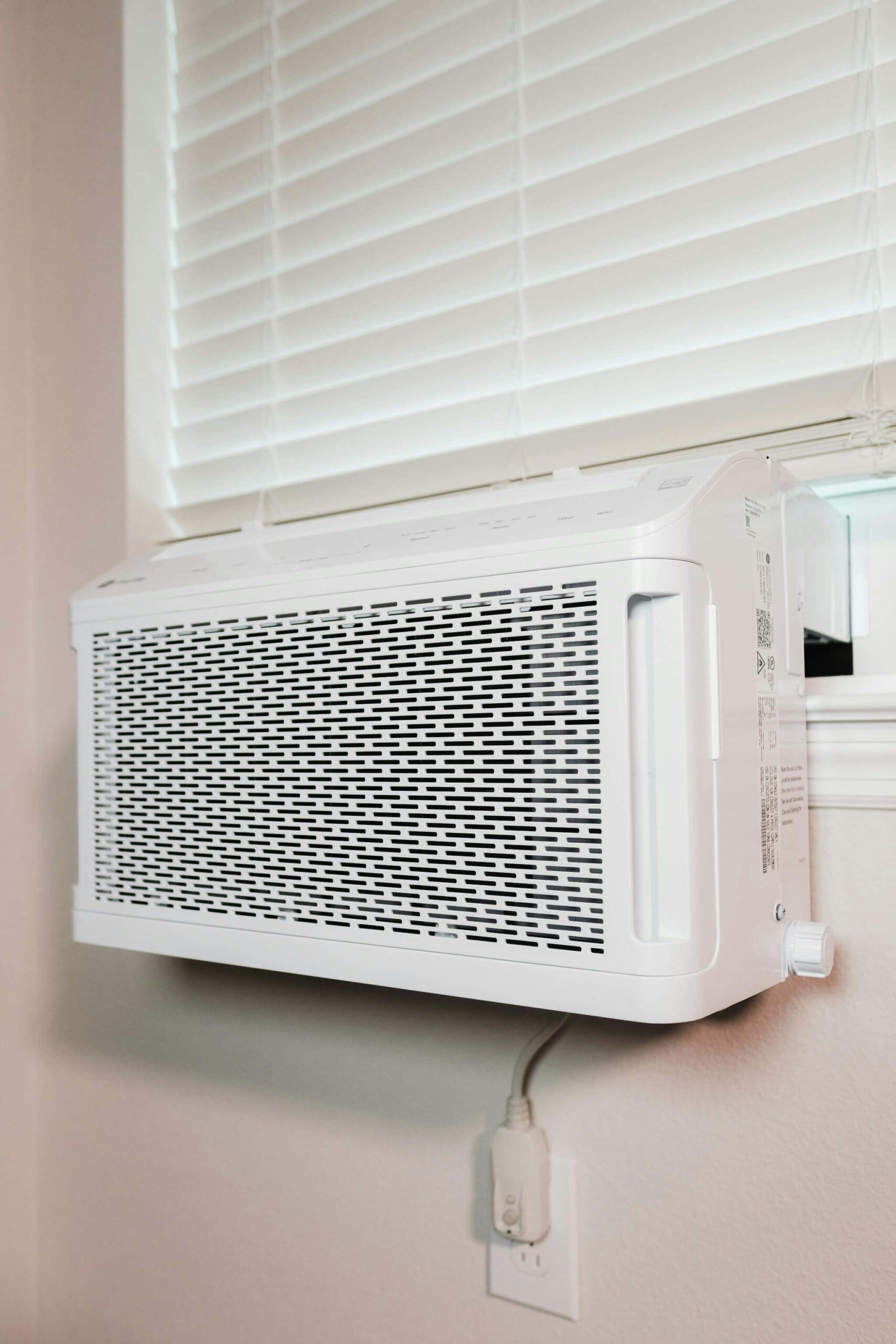 Window air conditioner picture below blinds.